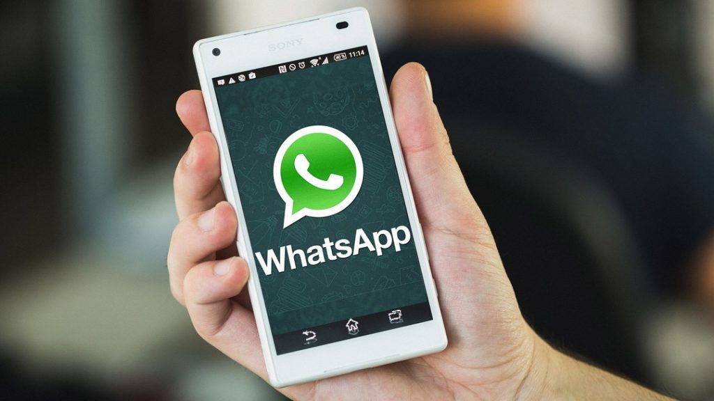 Imagen mano que sostiene teléfono celular con el logotipo de Whatsapp. Ofrecer un servicio de asistencia a través de WhatsApp. 